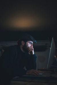 Side view of young man using computer at table