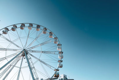 Low angle view of ferris wheel against clear blue sky