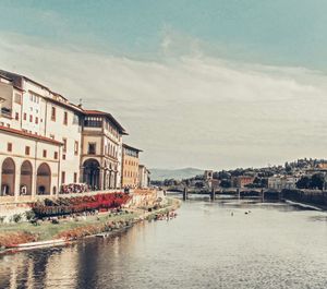 Buildings by river against sky