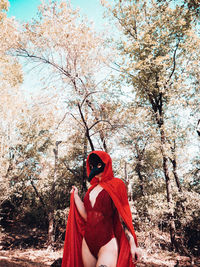 Portrait of sensuous woman wearing mask against trees