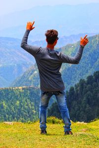 Rear view of man standing on landscape against mountain range