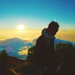 Side view of man standing against sky during sunset