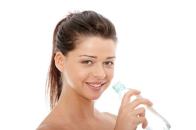 Portrait of a smiling young woman drinking against white background