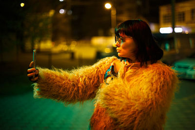 Portrait of young woman looking at illuminated camera