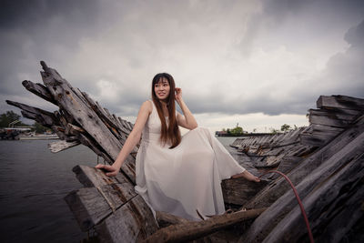 Portrait of woman sitting on beach against sky