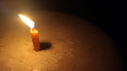 Close-up of lit candle in darkroom