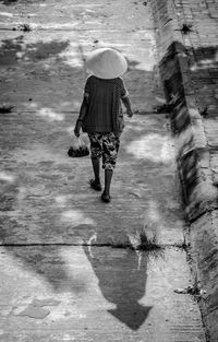 Rear view of woman walking on footpath by street