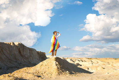 Low angle view of woman standing on mountain against sky