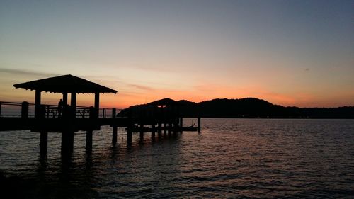Silhouette pier on lake against sky during sunset