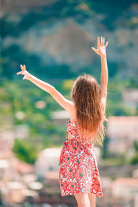 Rear view of woman with arms raised