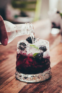 Close-up of hand pouring water in drink