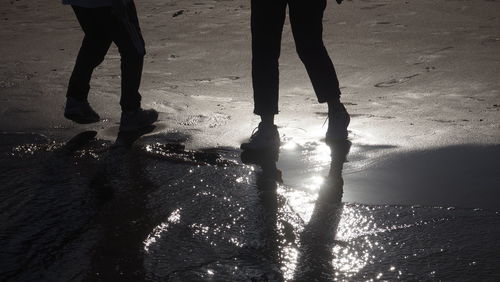 Low section of people walking on puddle