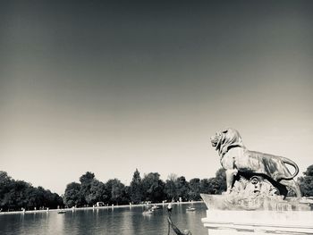 Statue in lake against clear sky