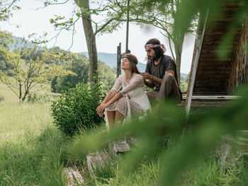 Attractive woman in a see-through dress looks away as her boyfriend braids her hair