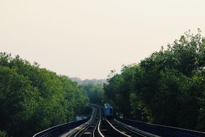 Railroad tracks amidst trees against clear sky