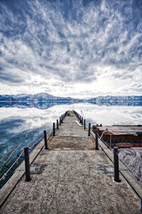 Pier over sea against cloudy sky