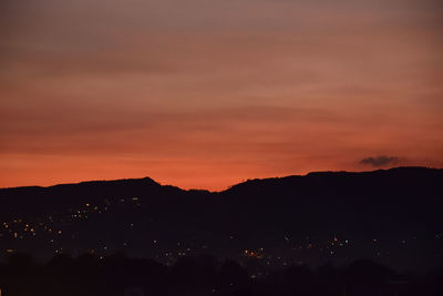 Silhouette landscape against dramatic sky during sunset