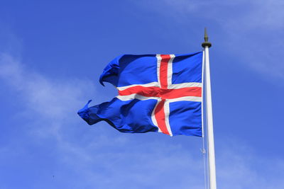 Low angle view of flag against blue sky