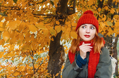 Dreamy woman with red hair and black eyes enjoying nature in autumn forest. yellow leaves.