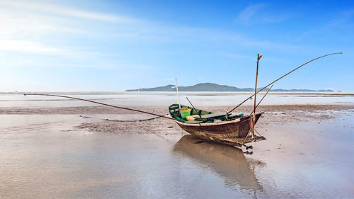 Boat moored on beach against sky