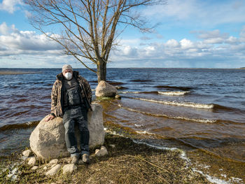 Rear view of man standing on beach against sky