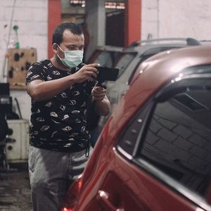 Man wearing mask photographing car