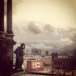 Man standing on city street against cloudy sky