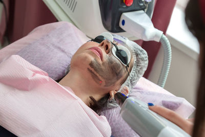 Facial cleansing procedure with carbon peeling in a spa salon.