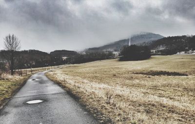 Road amidst field against sky