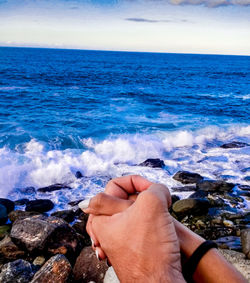 Midsection of man on rock at beach against sky