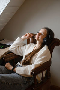 Young woman listening to music in big headphones near computer at home. creating play list, enjoying