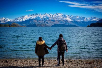 Rear view of people on snowcapped mountain against sky