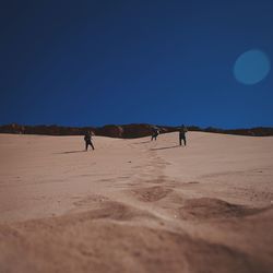 People standing in desert against clear sky