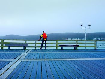 Man tourist in autumn mist on wooden pier above sea. depression, dark atmosphere. touristic mole, 