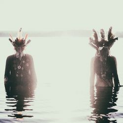 Indigenous people wearing costume while standing in lake