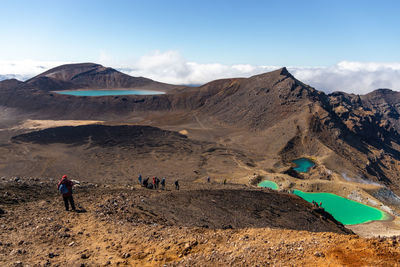 People on volcanic mountain against sky