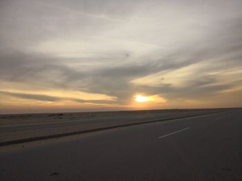 Road by sea against sky during sunset