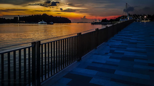 Pier in sea at sunset