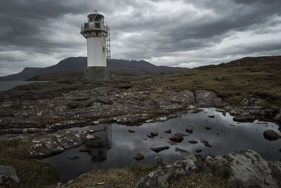 Reflection of lighthouse on water amidst rock formations