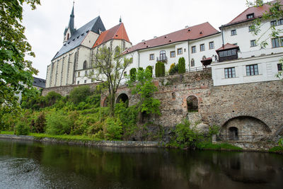 Arch bridge over river by building against sky