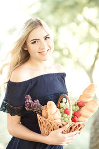 Portrait of smiling woman holding fruits in basket