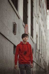 Portrait of young man standing against building