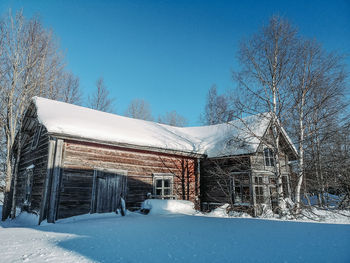 Snow covered house against clear blue sky