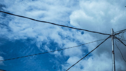 Low angle view of electricity pylon against blue sky