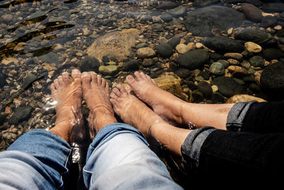 Low section of couple sitting in river