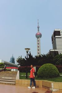 Rear view of man standing by building against sky