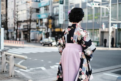Rear view of woman walking on road in city