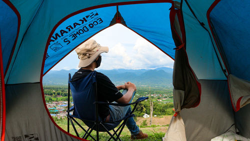 Rear view of man sitting on tent