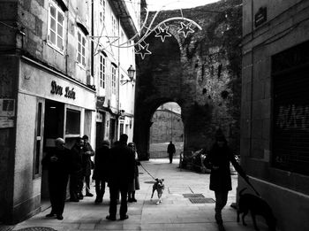 People walking on street amidst buildings in city