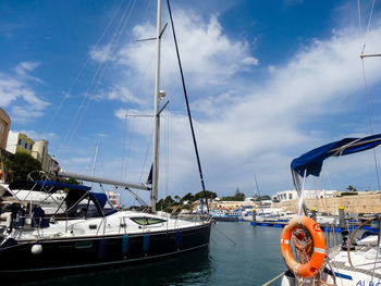 Boats moored at harbor against blue sky